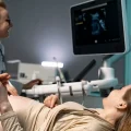 Ginecologista conduzindo ultrassonografia transvaginal com paciente deitada na maca