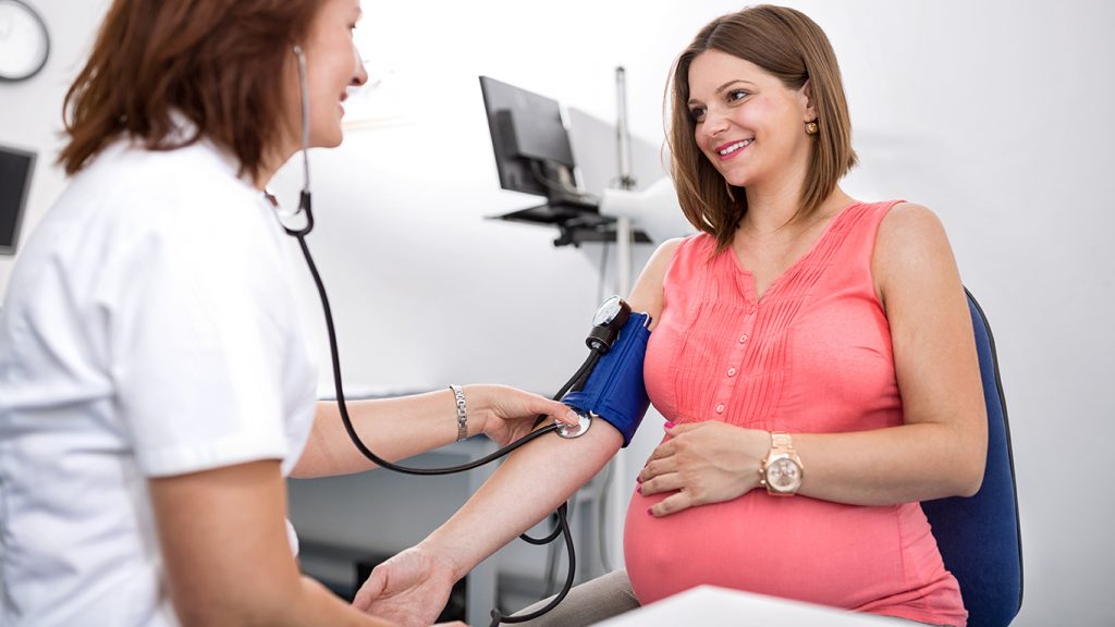 Médica fazendo o rastreamento da pré-eclâmpsia em paciente grávida