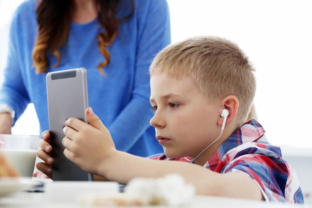 Imagem ilustrativa de criança com transtorno de dependência de tela usando tablet nas refeições.