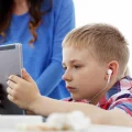 Imagem ilustrativa de criança com transtorno de dependência de tela usando tablet nas refeições.