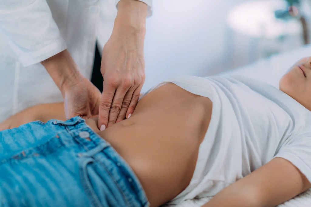 Pediatra realizando exame f&iacute;sico abdominal em crian&ccedil;a.