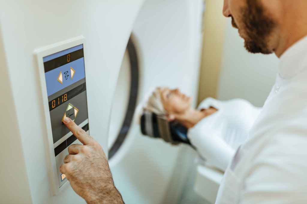 Close de um t&eacute;cnico m&eacute;dico iniciando um exame de resson&acirc;ncia magn&eacute;tica em uma paciente.