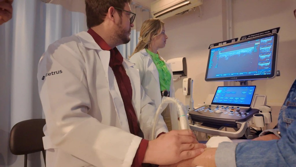 Médico em treinamento prático de ultrassonografia com acompanhamento de uma profissional em ambiente de ensino do Cetrus.